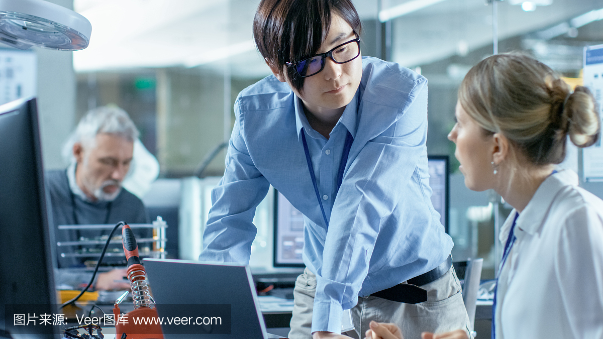 女計算機科學家用綠色屏幕模型連接電路板到她的筆記本電腦。她在先進技術實驗室工作。