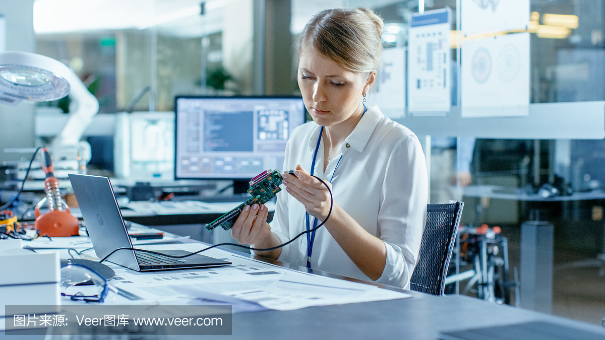 女計(jì)算機(jī)科學(xué)家將電路板連接到她的筆記本電腦并開始編程。她在先進(jìn)技術(shù)實(shí)驗(yàn)室工作。